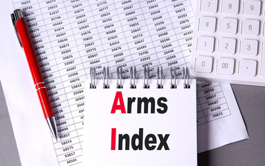 Arms index abbreviation written in notebook on desk with calculator, spreadsheet and red pen