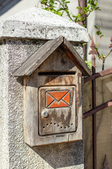 Weathered wooden parcel post box on a cement fence pole, on a sunny afternoon