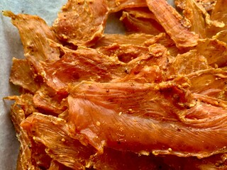 Slices of seasoned jerky are neatly arranged, displaying a rich color and savory spices. The...