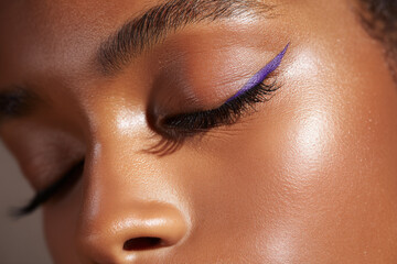Black woman with glowing deep skin tone and bold purple eyeliner makeup