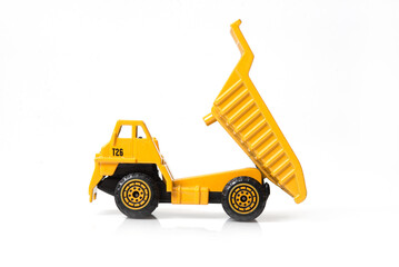 Yellow toy dump truck with tilted bed on white background. Construction vehicle model for kids or...