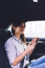 Cheerful young woman using smartphone in car