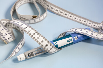 Ozempic syringe pen and measuring tape on blue