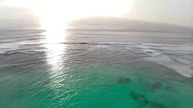 Sunlight shimmering on tropical ocean from high aerial perspective
