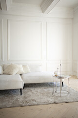 white sofa is standing near white wall background. gray couch on the floor. bedside table with decor, classic interior design, minimalism style. free space