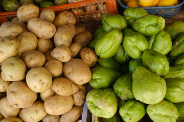 Potatoes and green vegetables in plastic trays at Bali market