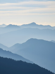 Naklejka premium Blue Mountain peaks against a misty morning sky, creating a dramatic mountain range effect artifacts visible.