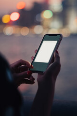 Crop young woman using smartphone with copy space screen on background of blurred night city