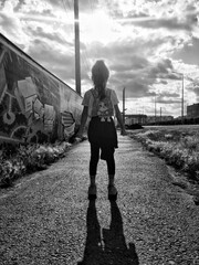 A girl from the back looks forward and her shadow falls on the asphalt
