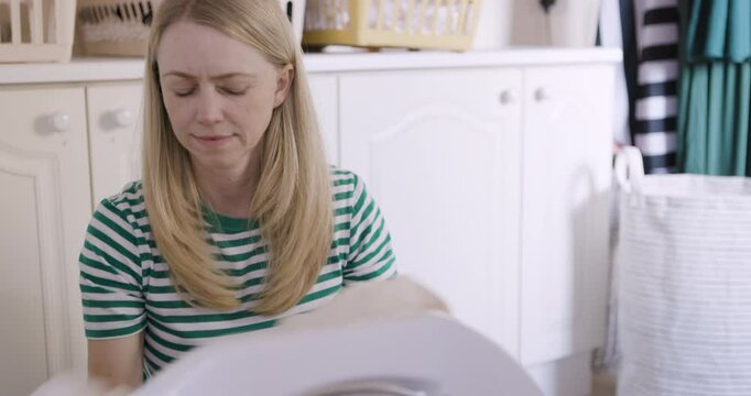 Mature woman, washing machine and doing laundry while loading clothes or fabric in front loader for cleaning at, home. Cleaner, housewife or worker doing spring cleaning for clean and fresh house