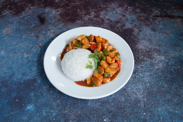 A plate of food with rice and meat. The rice is white and the meat is chicken. There are also peppers and carrots on the plate