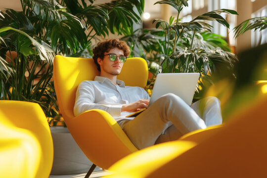 Relaxed Young Entrepreneur Working on Laptop in Modern Green Workspace