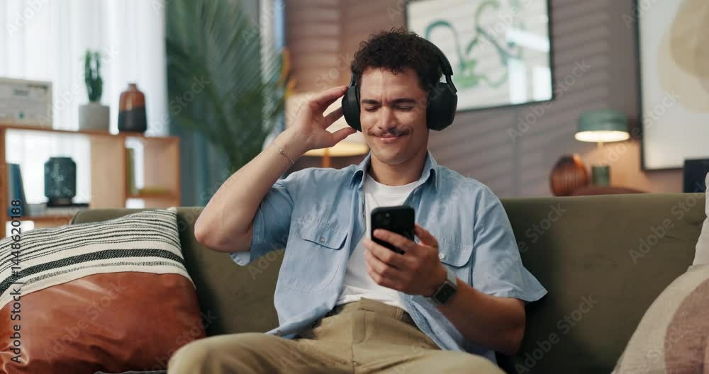 Poster headphones, dancing and man with phone on sofa in home for chatting, relaxing and listening to music