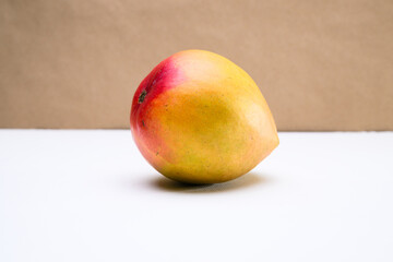 A mango on a white tabletop against a brown background