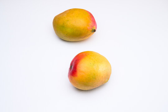 Two mangoes against a white background