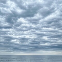 Fototapeta premium Serene ocean view under a cloudy sky with layered altocumulus clouds creating a peaceful and calming atmosphere reflecting nature's beauty and vastness