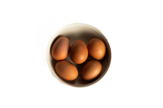 Five brown eggs in a white bowl, top-down view on a white background. - Powered by Adobe