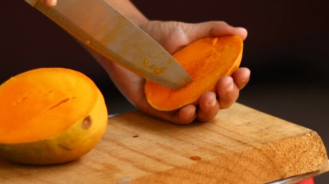 A close-up clip showing hands slicing a ripe mango into neat cubes using a knife and flipping it outward to display the juicy segments- preparation, healthy eating.