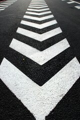 Asphalt Road with White Chevron Markings Leading Forward, Abstract Directional Pattern, Surface Texture, Transportation Concept, Urban Design, Geometric Precision, Contrast
