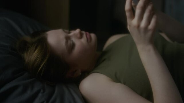 Close-up of young Caucasian woman lying in bed and looking at photos with beloved man, crying in pain after breakup, past memories hurting emotionally