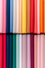 Vibrant rolls of colorful fabrics, arranged in neat rows, create a visually appealing and textured pattern. Great for sewing projects and creative crafts.
