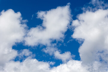 White cumulus clouds drifting across a vibrant blue sky