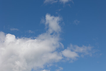 Fototapeta premium White clouds drifting across a vibrant blue sky