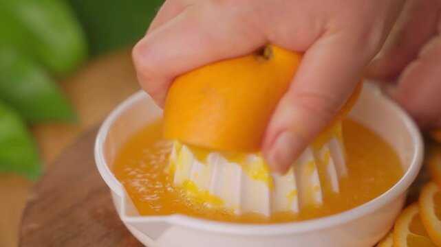 Hand juicing an orange half on manual citrus squeezer