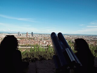 The girls silhouettes at the top of the viewpoint with the city and mountains in the background.