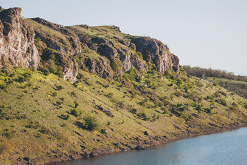 Nature's serenity captured along a tranquil riverbank in a sunlit landscape filled with lush...