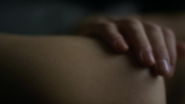 Extreme close-up of male hand softly and tenderly stroking female arm and shoulder in moments of feeling deep love, serene and peaceful atmosphere