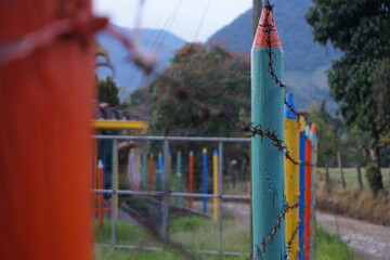 Colorful wooden fence with barbed wire in rural Colombia, mountains in background on sunny day