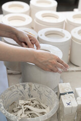 Hands working on a pottery mold with various ceramic pieces