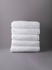 stack of white terry towels on grey background