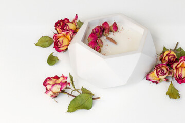 aromatic candle with wooden wick in plaster candlestick decorated with roses, close-up on white background, handmade concept