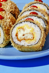 Tempura maki sushi rolls with cheese and crab filling lying on blue plate