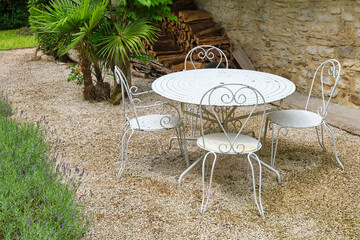 Classic old white metal bistro chairs and table in a garden in the village of Cornac Lot Occitanie in Southern France 