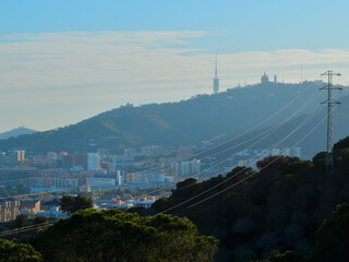 Power lines in mountain. Cityscape with Tibidabo in background, in Barcelona, Spain.