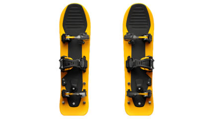 A pair of yellow snowshoes with black straps and bindings isolated on a black background in a studio shot