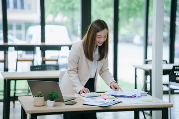 Businesswoman working in office with documents and laptop. Employee documents calculate financial...