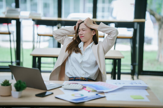 A close-up of an Asian woman holding the credit card and her smartphone while sitting indoors