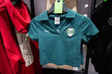 Fototapeta premium Green Slytherin themed cropped Puma shirt displayed on clothing rack among other apparel items