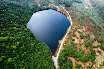  Aerial view of Bay Lough, a heart-shaped mountain lake nestled in the Knockmealdown Mountains near The Vee Pass in County Tipperary, Ireland, surrounded by lush forests and rugged terrain.