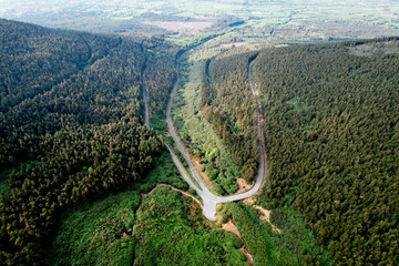  Aerial view of The Vee Pass winding through the Knockmealdown Mountains, showcasing stunning Irish landscape, vibrant greenery, and dramatic elevation in County Tipperary, Ireland.
