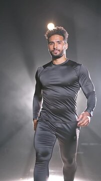Athl&egrave;te concentr&eacute; marchant sous les projecteurs en tenue de sport noire