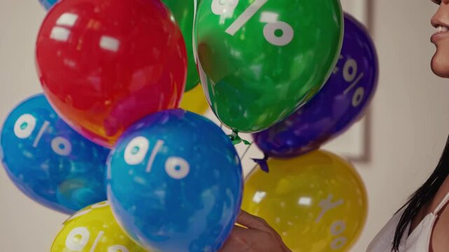 Female consumer holding vibrant balloons displaying percentage signs, symbolizing dynamic retail promotions, discounts, and shopping excitement