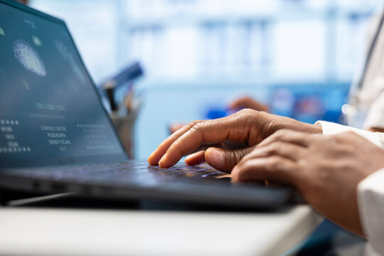 Medical professionals meeting in a private clinic to review healthcare data on laptop. Specialists with licensed expertise guide effective treatment plans and diagnostics, teamwork. Close up.