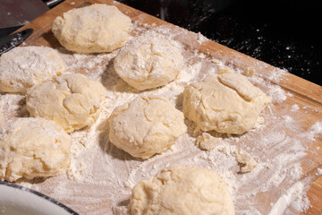 Irregularly shaped dough pieces dusted with flour rest on a wooden surface, ready for baking or cooking.