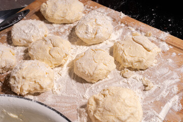 Irregularly shaped dough pieces dusted with flour rest on a wooden surface, ready for baking or cooking.