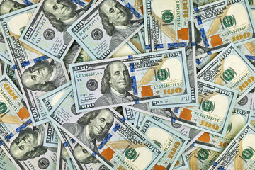 A pile of one hundred US dollar bills scattered randomly, symbolizing wealth, success, investment, and financial abundance in a modern economy.